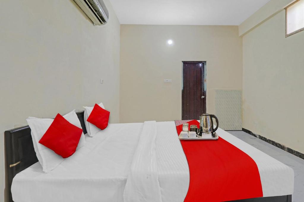 a bedroom with a white bed with red pillows at Hotel O by OYO Sunrise Inn in Gorakhpur
