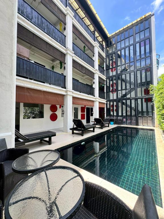 a building with a swimming pool and two tables at 99 The Gallery Hotel in Chiang Mai