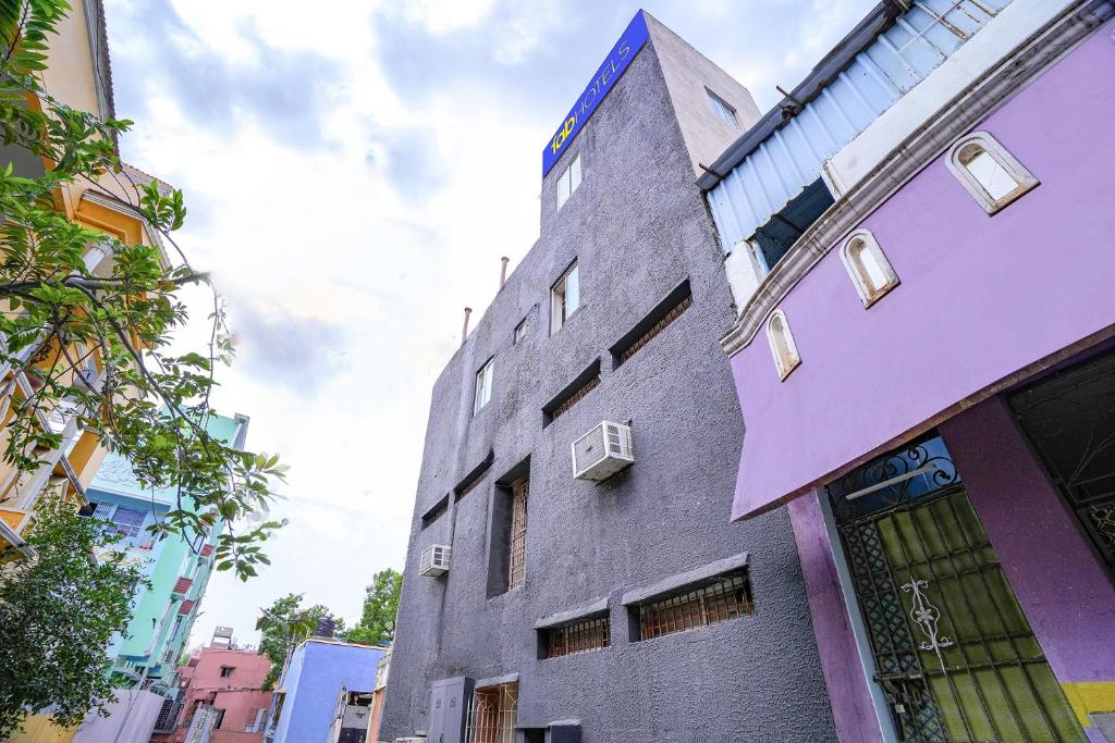 a tall gray building with windows on a street at FabHotel Mara Residency in Chennai