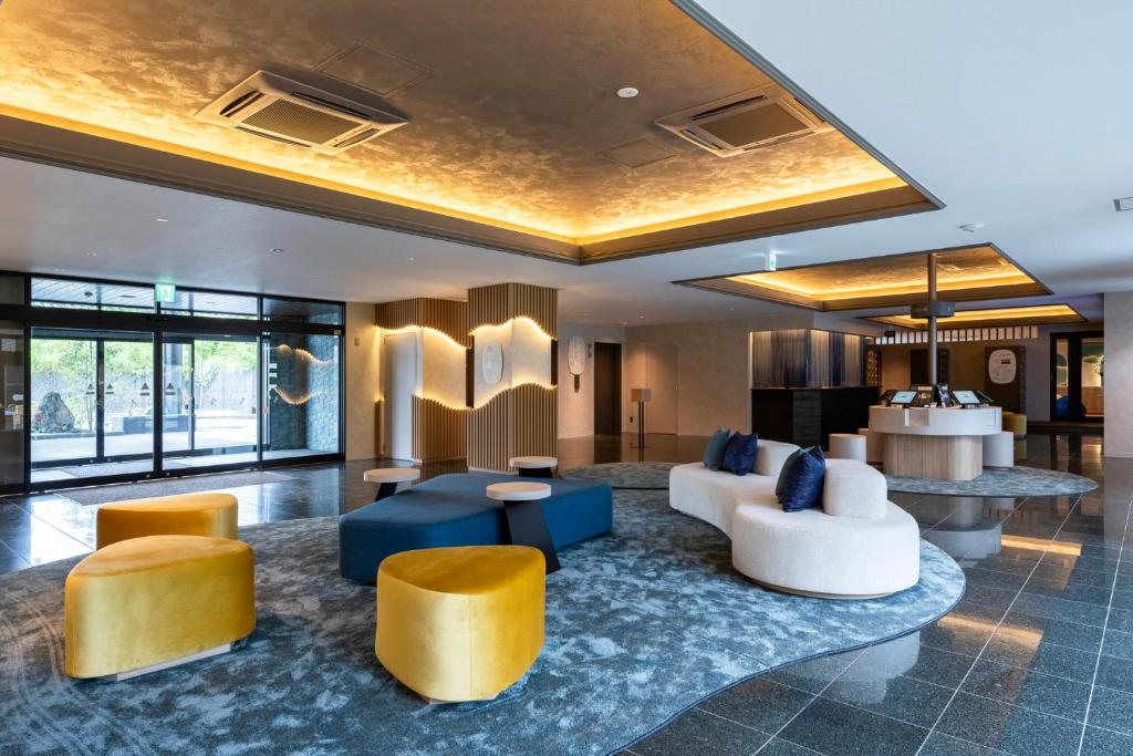a lobby with couches and chairs and a table at BbyC HOTEL Kusatsu in Kusatsu