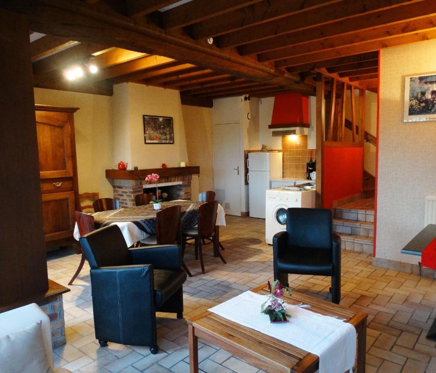 sala de estar con mesas y sillas y cocina en Gîtes de la Ferme Auberge de Mésauboin, en Billé