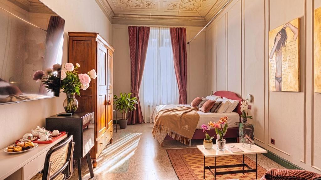 ein Hotelzimmer mit einem Bett und einem Tisch mit Blumen in der Unterkunft Homeby, Cinisca Suites in Bologna