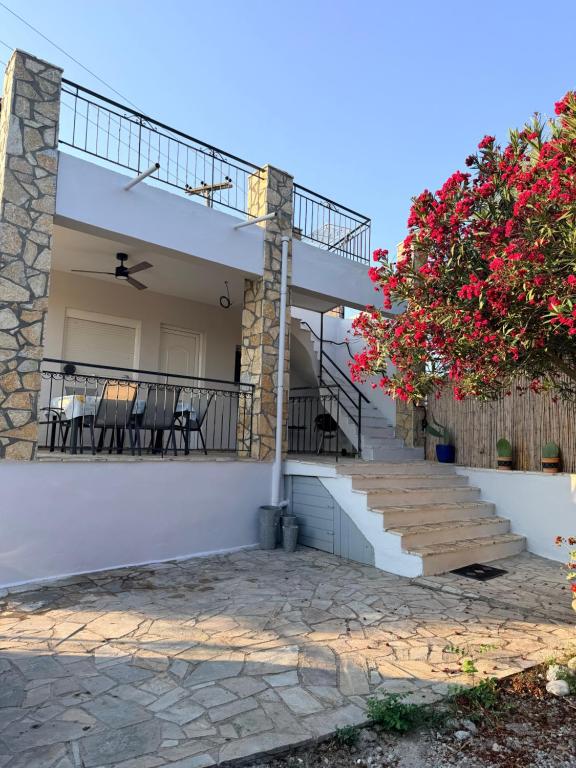 a house with stairs and a balcony with red flowers at Maison Pelops Petalidi in Petalidi