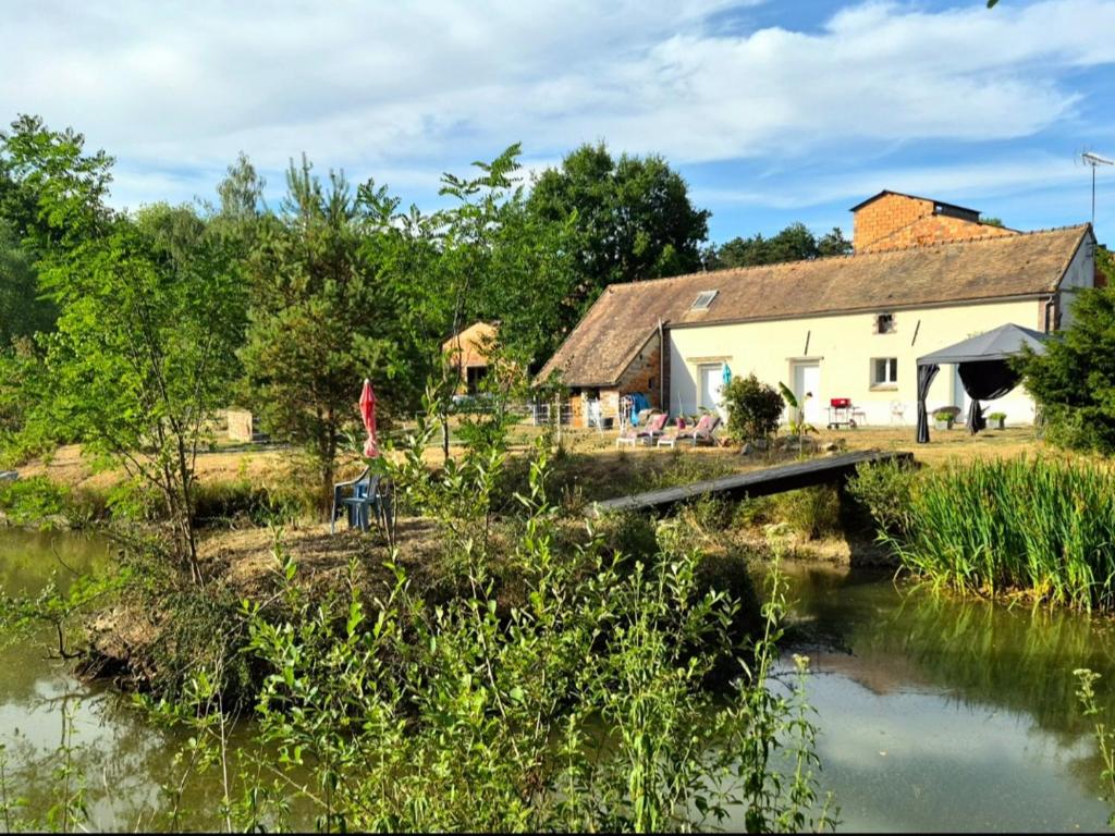 a house with a bridge next to a river at La Tuilerie Lixy Brannay in Brannay