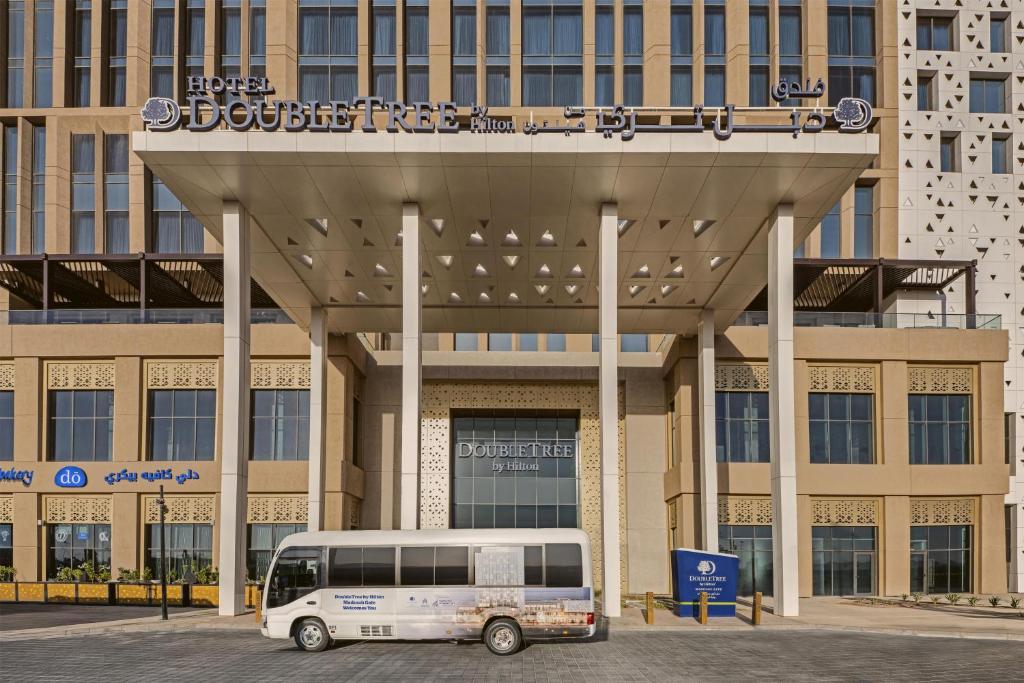 a white bus parked in front of a building at DoubleTree by Hilton Madinah Gate in Medina