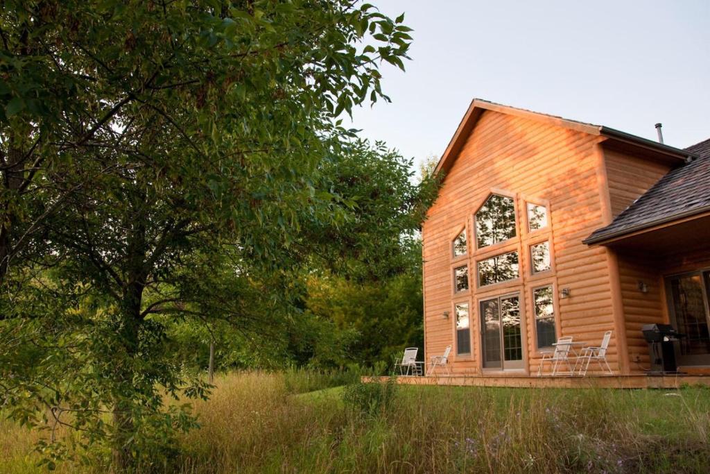a wooden house with chairs on the porch at Chanticleer Cabins in Sturgeon Bay