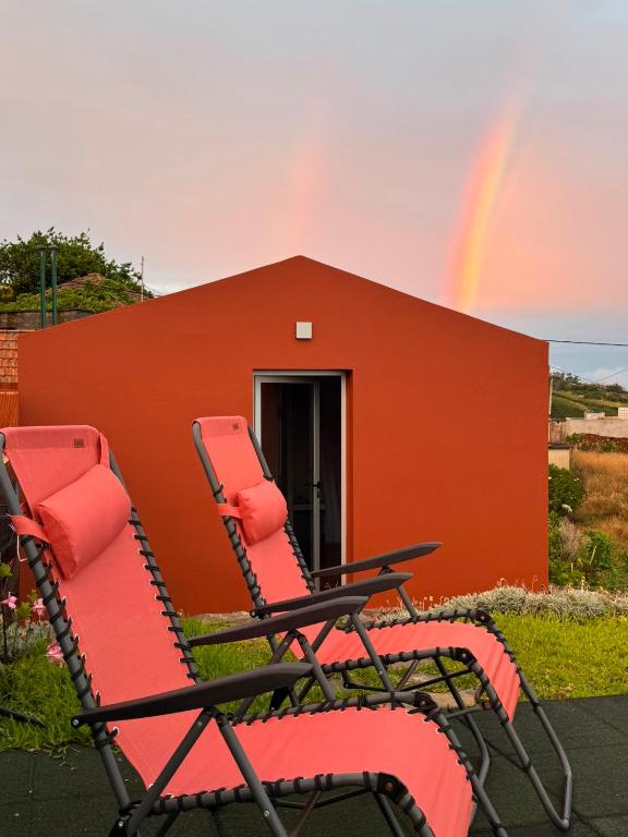 a pair of chairs sitting in front of a building with a rainbow at Casas do Pargo - Casa B Palheiro in Ponta do Pargo