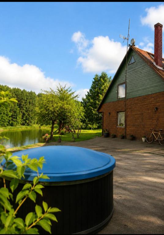 a large barrel in front of a house and a lake at Šilas in Degučiai