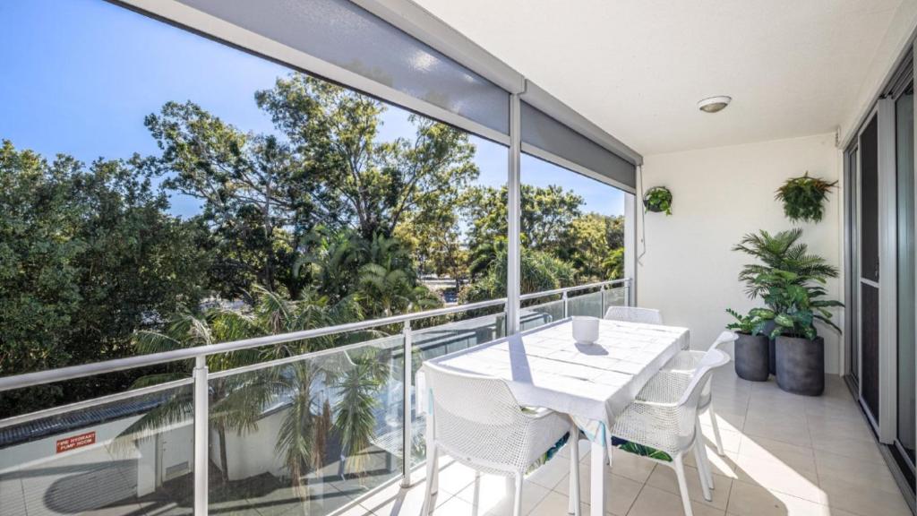 a balcony with a white table and chairs at Whispering Waves On Boyd in Woorim