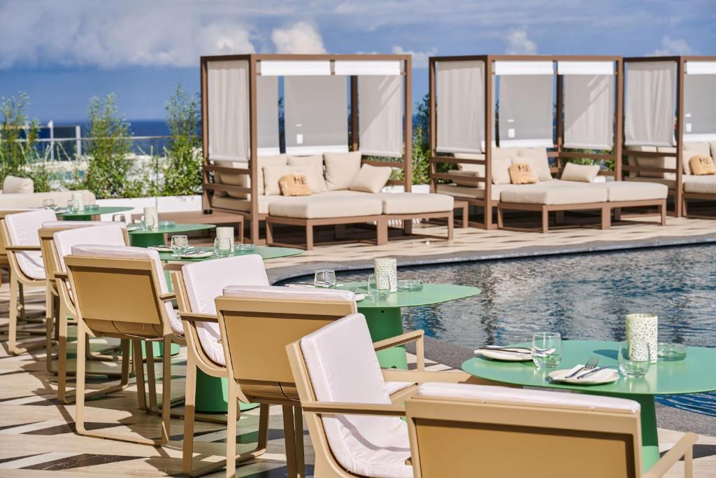 a restaurant with tables and chairs next to a pool at ME by Meliá Malta in St. Julianʼs