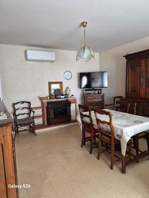 a dining room with a table and chairs and a television at maison village in Xambes