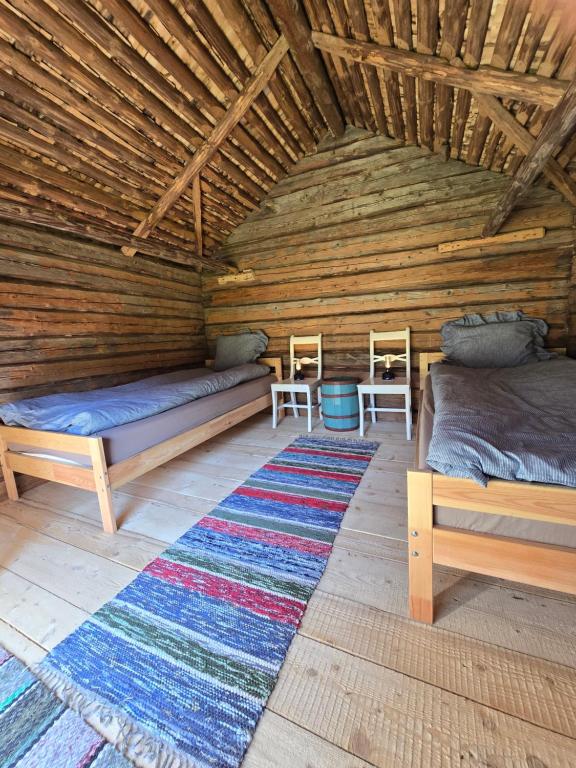 a room with two beds and a rug in a log cabin at Stockboden Kvarken Off Grid Cabin No Electricity or Running Water in Oravais