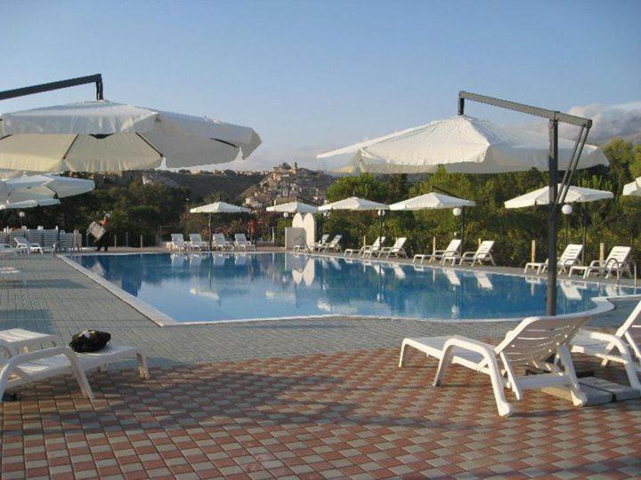 a large swimming pool with white chairs and umbrellas at Pantera Rosa Village in Scalea