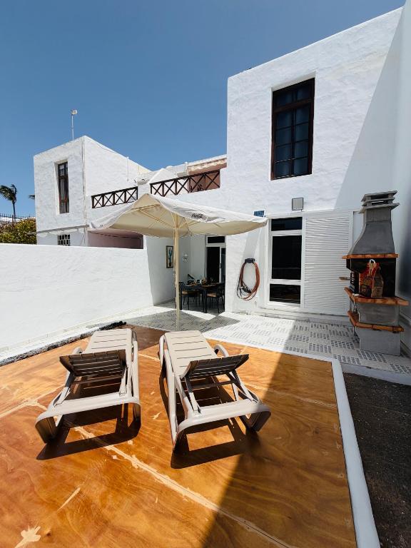 a patio with two lounge chairs and an umbrella at Casa TIN TIN Lanzarote in Tías
