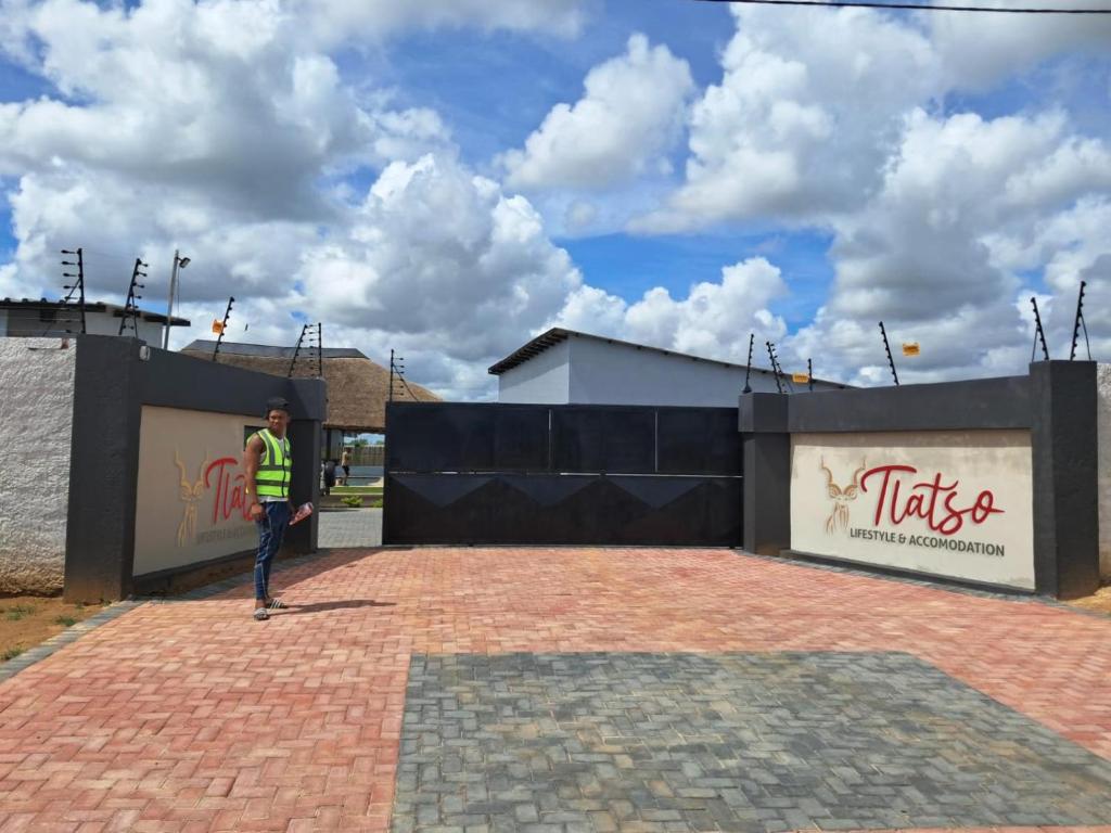 a man is standing in front of a fence at Tlatso lifestyle and Accommodation in Hammanskraal Station