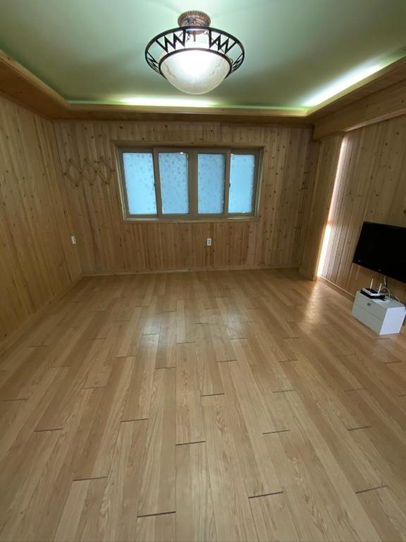 an empty room with wood floors and a chandelier at 신화펜션 in Koryŏng
