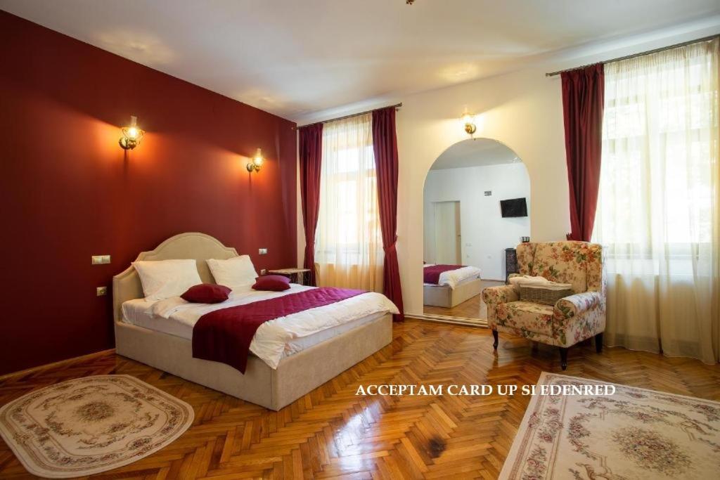 a hotel room with a bed and a chair at Margarethengasse Comfort Rooms Old Town in Sibiu