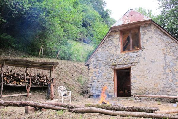 a stone house with a table and a chair in front of it at Cabane du Serris - Expérience insolite dans les Pyrénées in Beaudéan