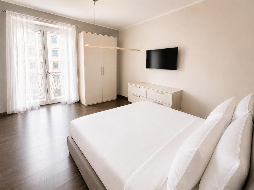a bedroom with a white bed and a flat screen tv at Porta Nuova Studio - Sostify in Bergamo