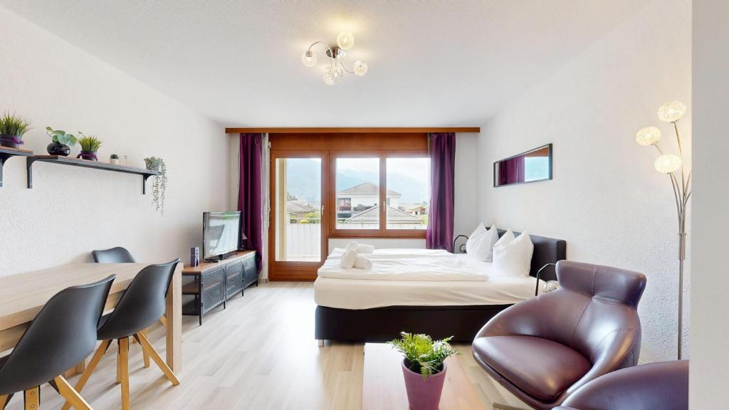 a hotel room with a bed and a table and chairs at Bright studio in Saillon, a few steps from Les Bains in Saillon