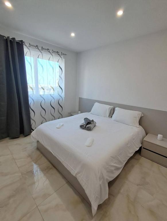 a white bedroom with a large white bed and a window at Caterina Suites in Wied l-Arkata