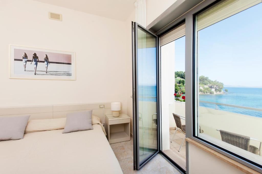 a bedroom with a bed and a view of the ocean at Baia D'Argento in Porto Santo Stefano