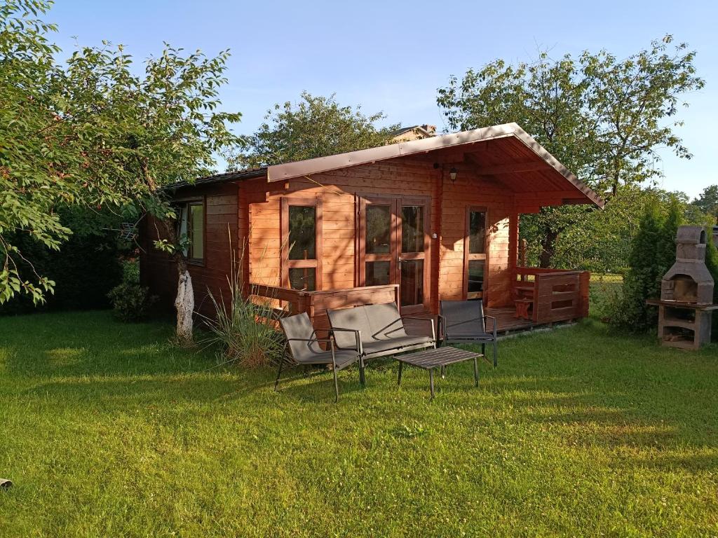 a log cabin with chairs and a table in the grass at Domek letniskowy u Bodzia in Kruklanki