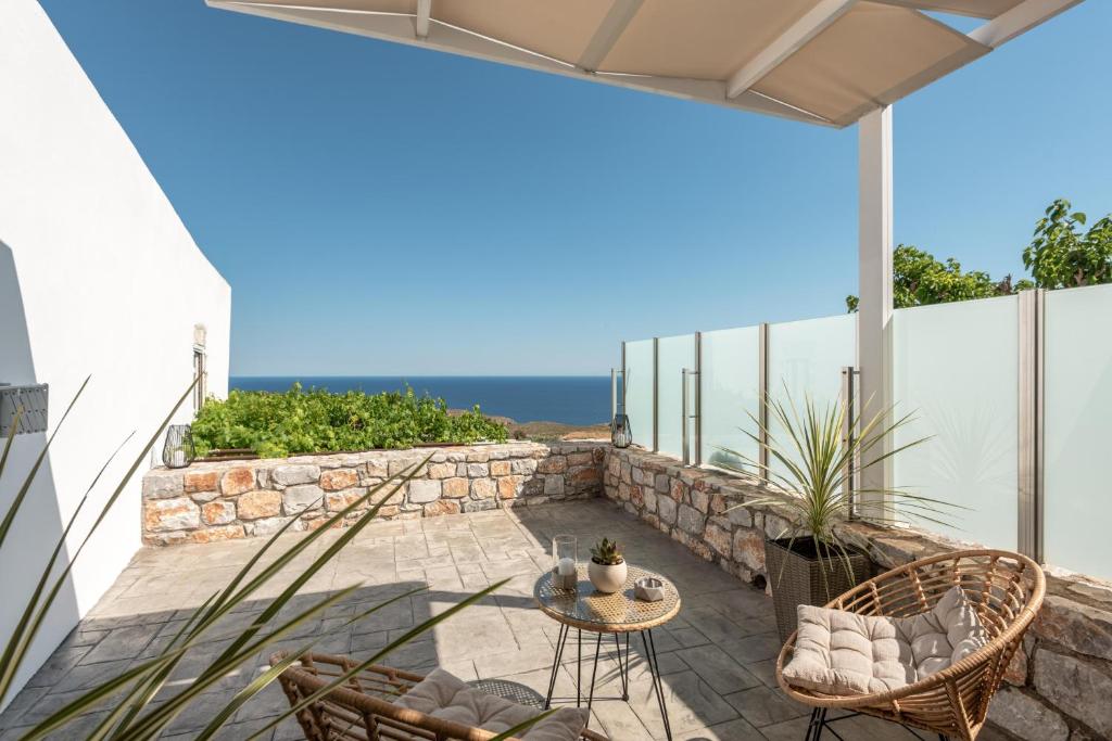 a patio with a table and chairs and the ocean at Tholos Home Sfakia in Hora Sfakion