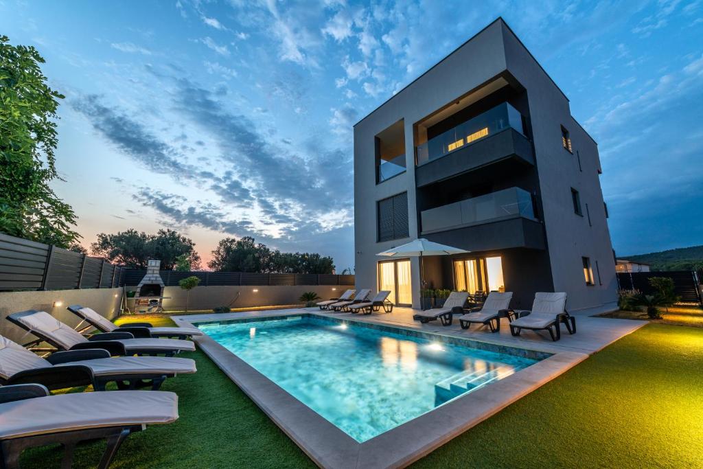 a house with a swimming pool and lounge chairs at Sunny Oasis in Bibinje