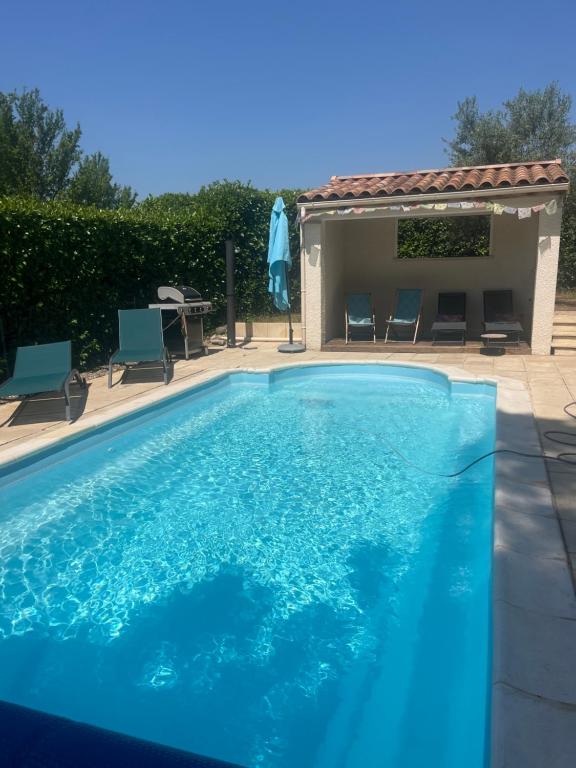 a blue swimming pool with chairs and a table at "Villa du Pin" idéalement situé Ruoms à pieds, voie verte in Ruoms