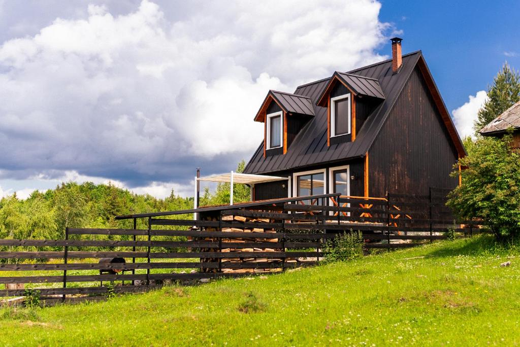 a black house on a hill with a fence at Cabana Foxes' Shelter din Beliș, Apuseni in Călăţele