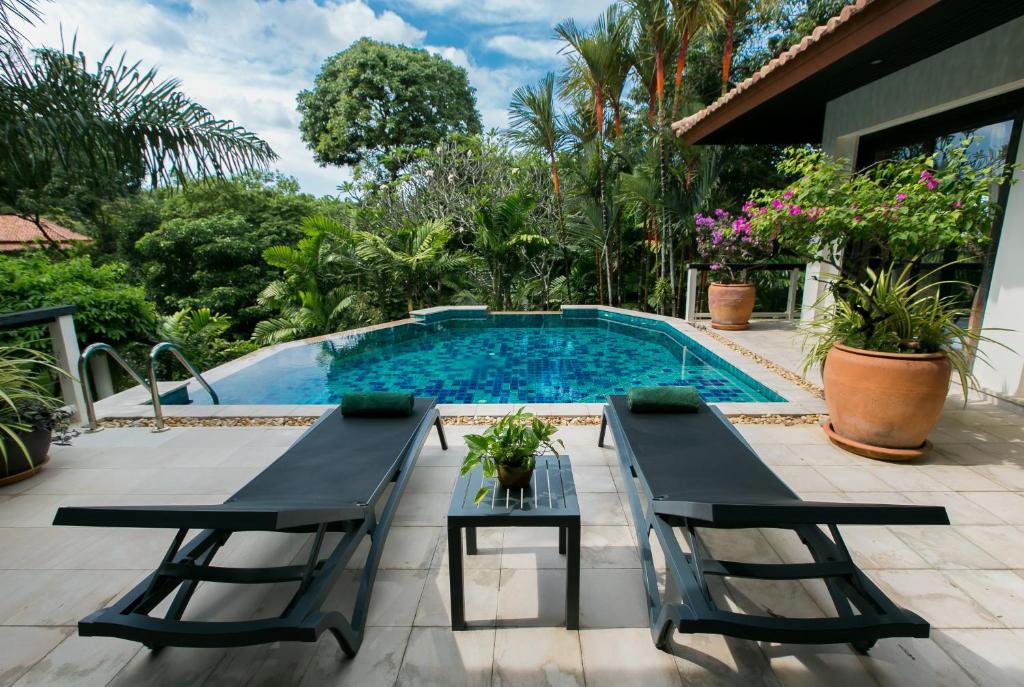 a patio with a table and chairs next to a swimming pool at Katamanda Villa Chanti Pool Villa Kata in Kata Beach