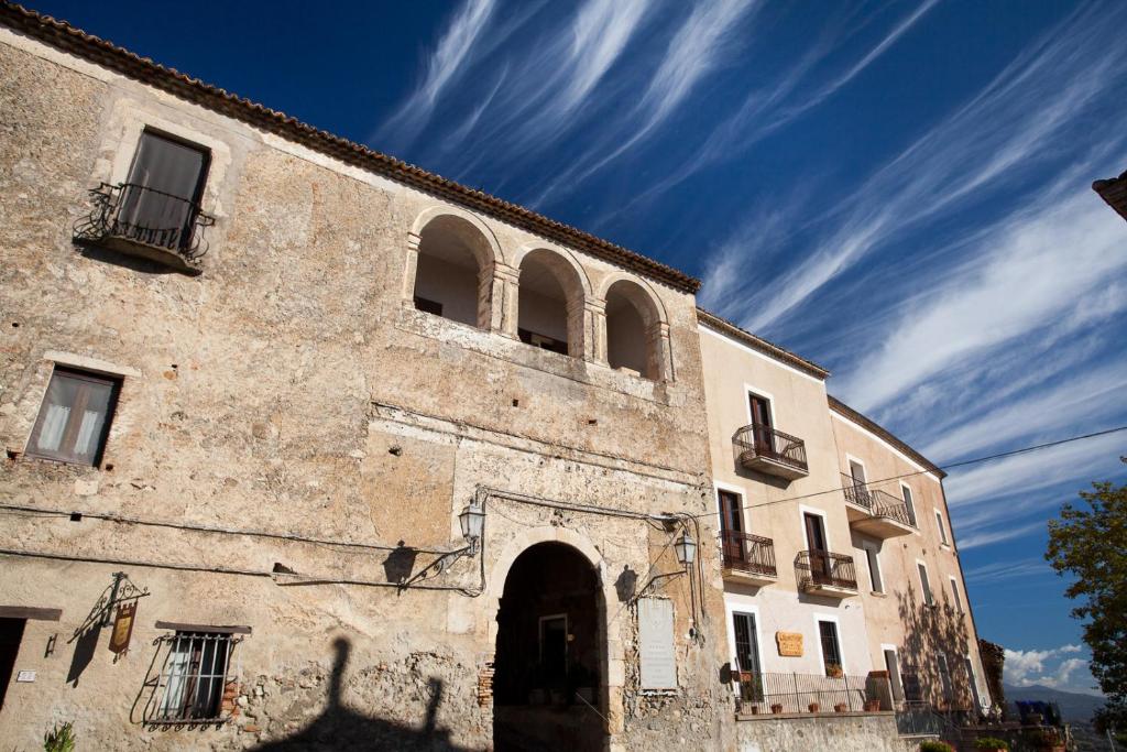 un ancien bâtiment en pierre avec un ciel bleu en arrière-plan dans l'établissement Castello di Altomonte, à Altomonte