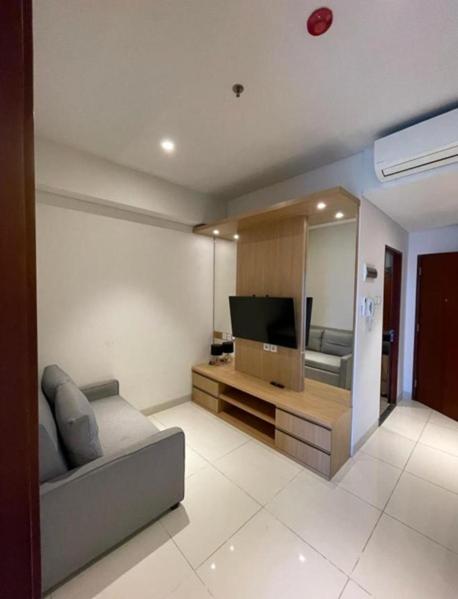 a living room with a couch and a television at Apartemen Roseville at BSD by Kenkei in Dadap