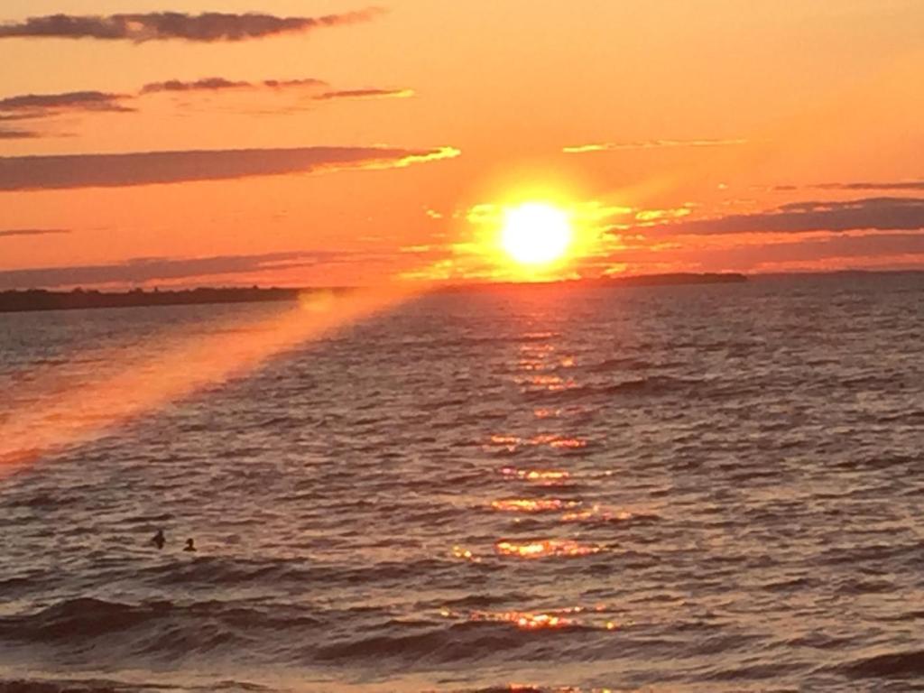 una puesta de sol sobre el océano con la puesta de sol en Les pieds dans le sable, en Chambord