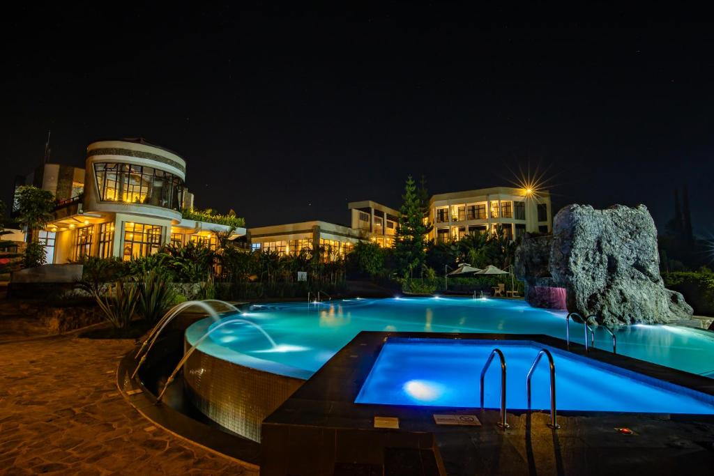 a swimming pool in front of a building at night at Grotta Resort in Gasanze