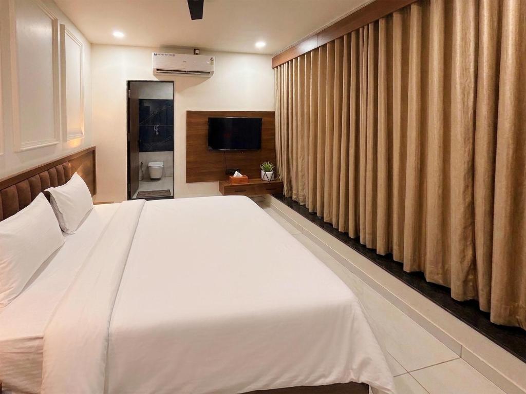 a bedroom with a large white bed and curtains at Hotel Vivanta in Bānswāra
