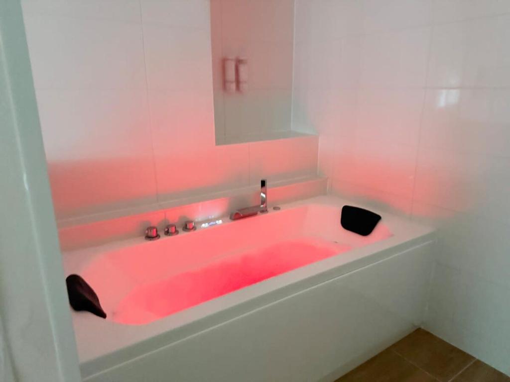 a pink bath tub in a bathroom with a mirror at Jacuzzi privé - Netflix - Wi-Fi - parking gratuit in Châtel-Guyon