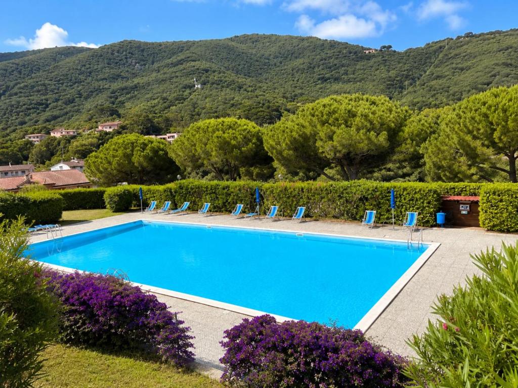 a swimming pool with chairs and a mountain at Cala Rossa 35 Wit Pool - Elba Affitti in Nisporto