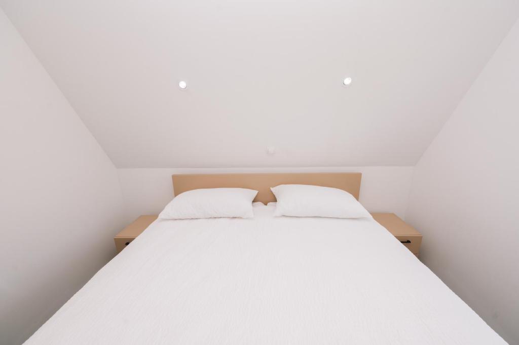 a bedroom with a white bed with two pillows at Vila Paola in Kupres
