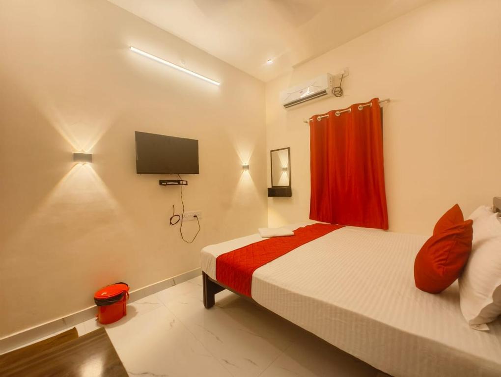 a bedroom with a bed with a red curtain and a tv at MKR GRANd in Rāmeswaram