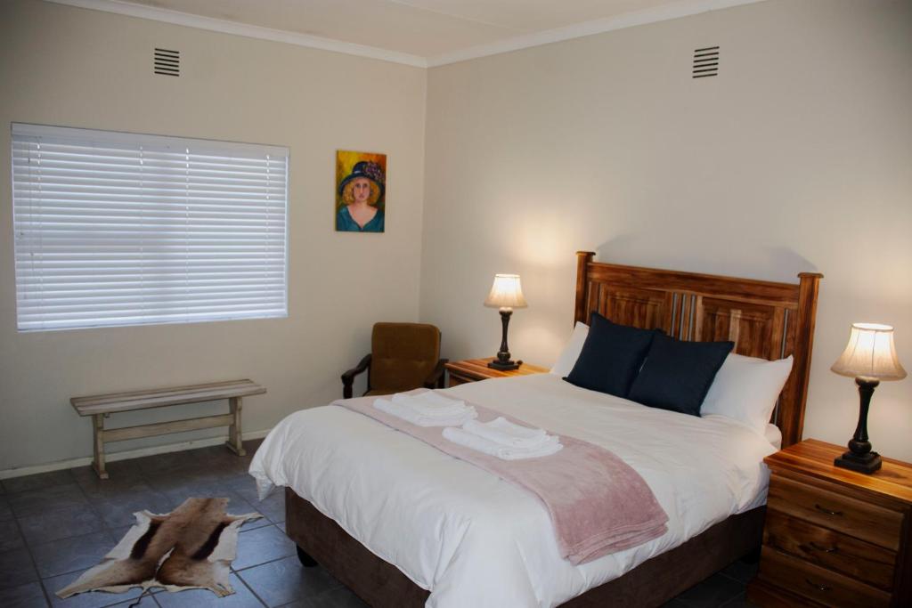 a bedroom with a large bed and two lamps at Tooiselvere in George