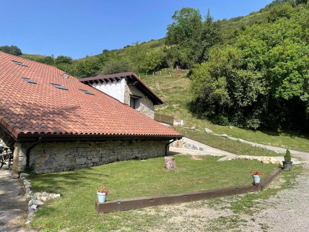 a building with a red tile roof next to a hill at Altxerri Baserria in Aia