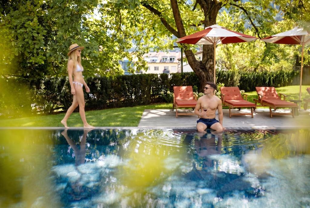 a woman walking next to a boy in a swimming pool at Castel Sallegg Suites Adults only in Caldaro