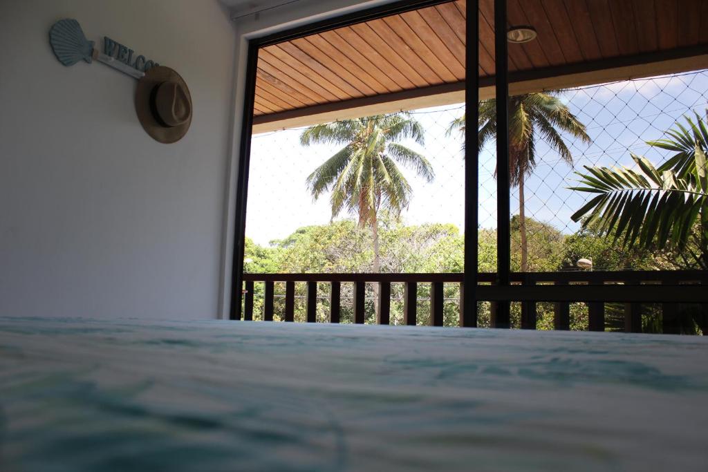 Schlafzimmer mit Blick auf eine Palme in der Unterkunft Nannai Residence - Muro Alto in Porto De Galinhas
