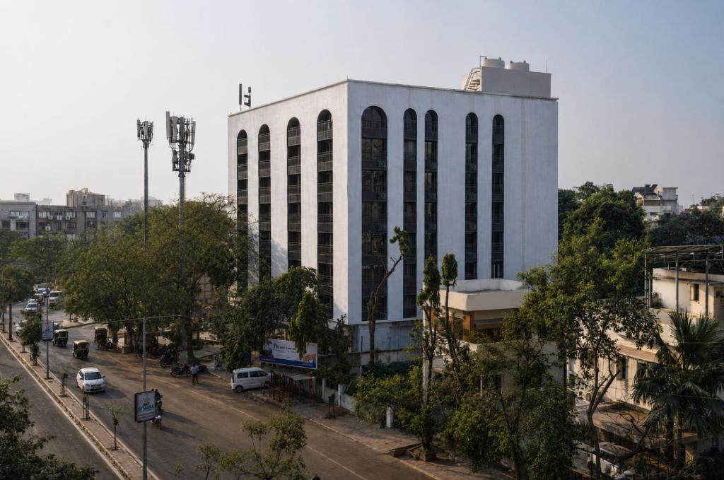 a large white building on a city street with cars at FLH Residences, Ambawadi in Ahmedabad