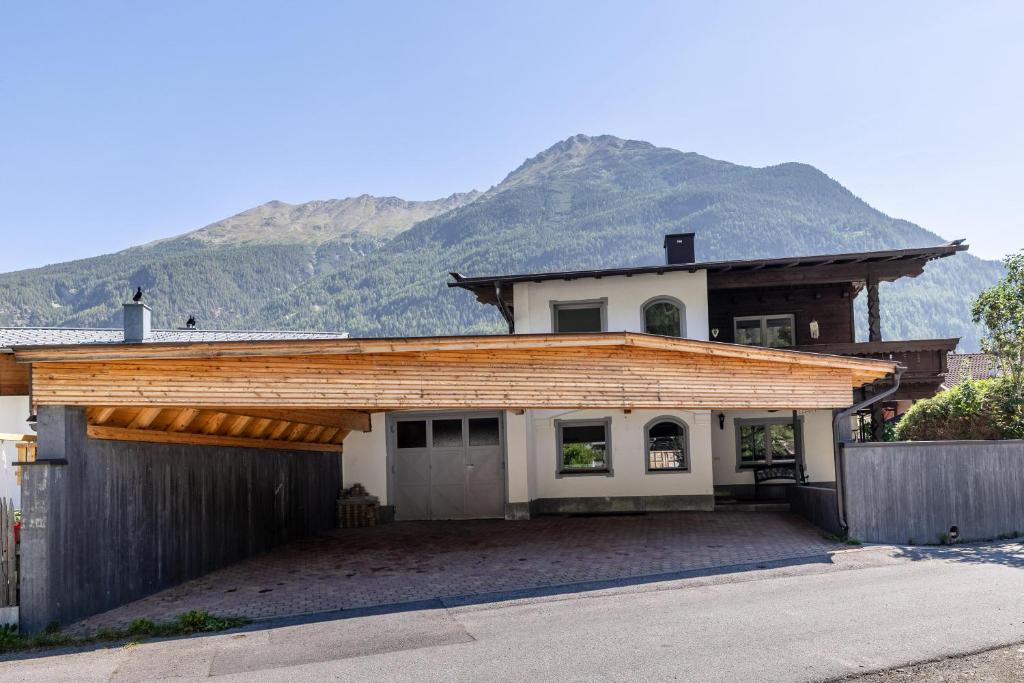 a house with a garage with a mountain in the background at LIDA CHALET in Längenfeld
