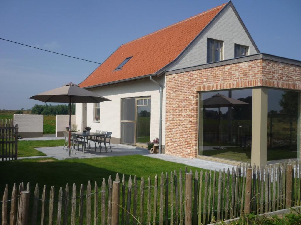 a house with a fence and a table with an umbrella at Toetindroaj in Kortemark