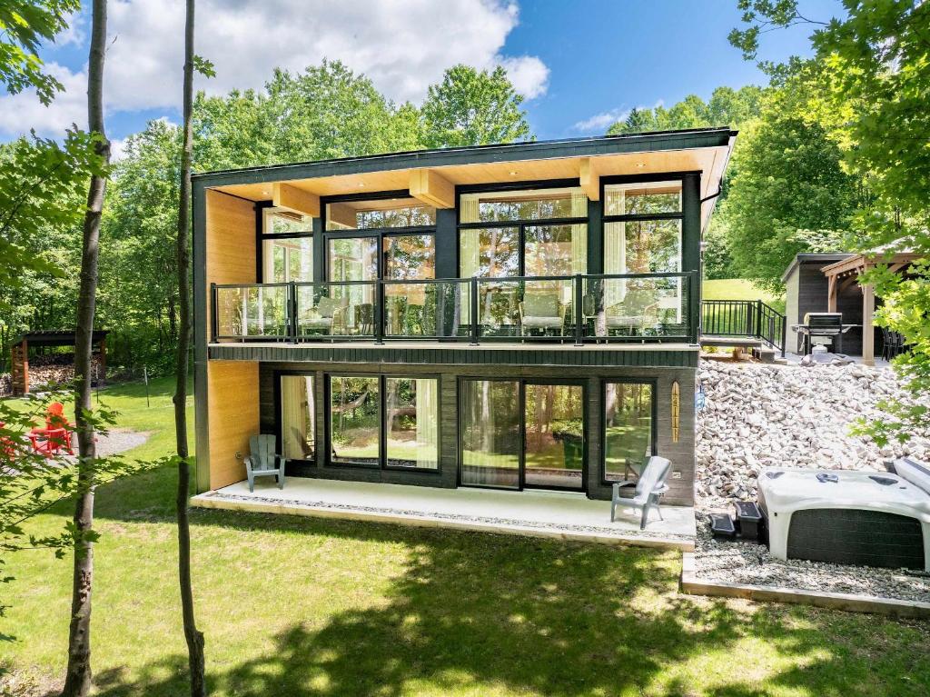a house with a large deck and glass windows at Chalet Mid-Century - Lakeside Joseph - Le Charlo in Saint-Pierre-Baptiste