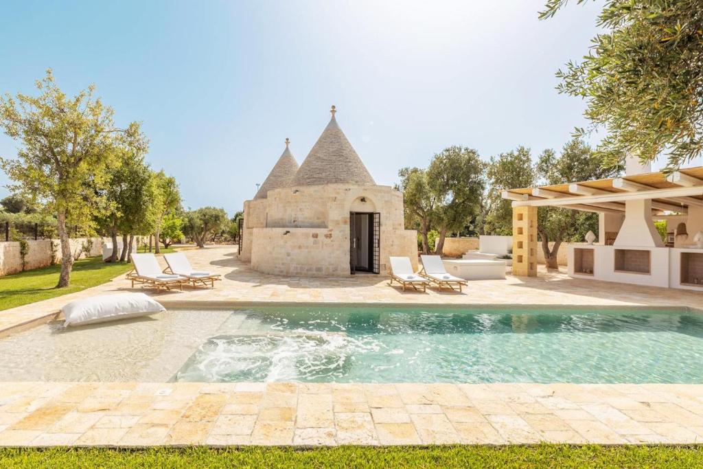an outdoor swimming pool in front of a building at Villa Trulli del Gelso in Carovigno